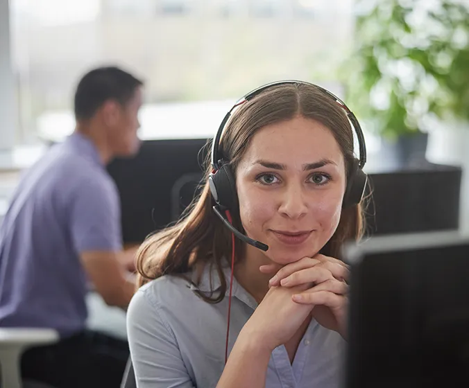Jasmine som är volontär på Mind i kontorsmiljö. Han har ett headset på sig och ser rakt in i kameran med en varm blick.