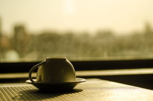 upp och nervänd kaffekopp på ett bord vid fönster